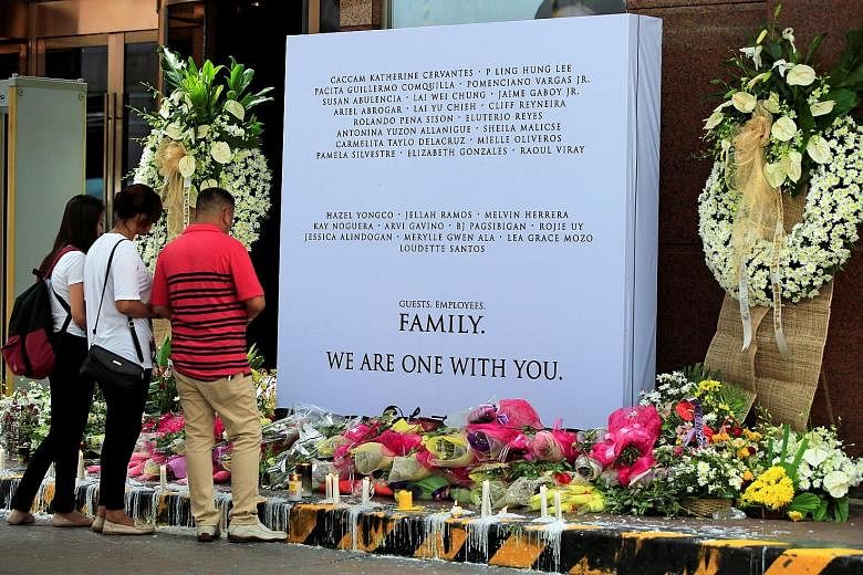 Employees paying their respects to those killed in the casino fires, at a memorial at Resorts World Manila on Sunday. Gunman Jessie Javier Carlos set alight a number of rooms at the complex, claiming the lives of 37 people.