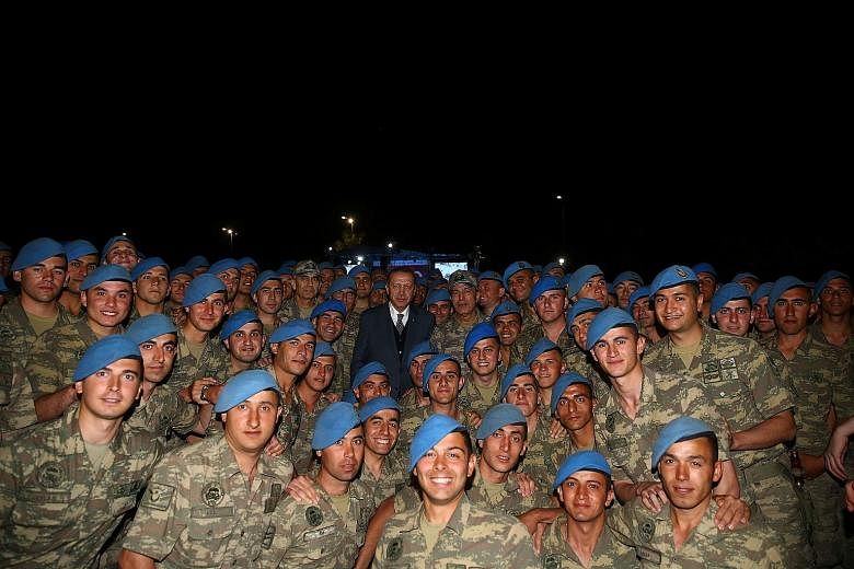 Turkish President Recep Tayyip Erdogan with commandos after an iftar - the breaking of the daily fast during Ramadan - in Kayseri, Turkey, on Thursday. Mr Erdogan rapidly approved a Bill to deploy troops to Qatar after it was pushed through Parliamen
