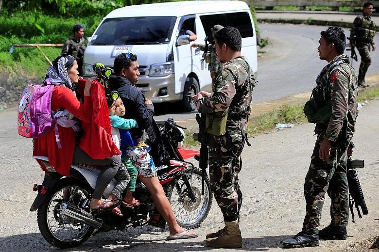 Philippine National Police Special Action Force personnel man a checkpoint in Marawi city as government troops continue their assault against the Maute group. Romato Maute, or Farhana (far left) was arrested on Friday, days after her husband, Cayamor