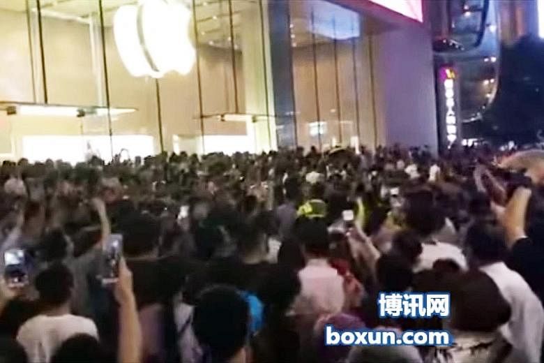 A screengrab of people snapping shots (above) of police detaining protesters outside the Apple store in Shanghai, whose shopping district was overrun by demonstrators (left) on Saturday.