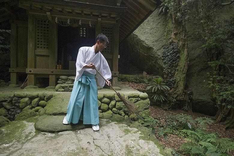 A Shinto priest sweeping at an ancient shrine in Okinoshima, an island in Fukuoka prefecture, on Friday. Okinoshima, which is located between Japan and Korea, will be officially designated as a Unesco World Heritage Site next month, as it is one of t