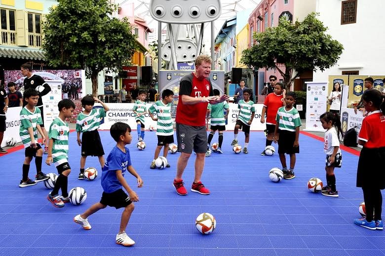 Bayern youth coach Thomas Dollner showing children the basics of dribbling, shooting and passing at a free public football clinic yesterday.