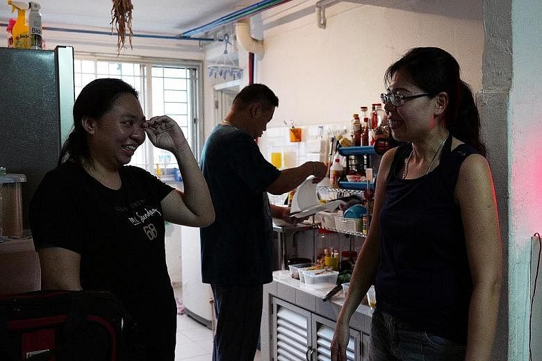 Ms Tang Zhi Ling (far left) and Ms Vivian Pan at the former's flat in Henderson Road. In the background is Mr Ricky Ng, 47, who belongs to Ms Pan's group of volunteers.