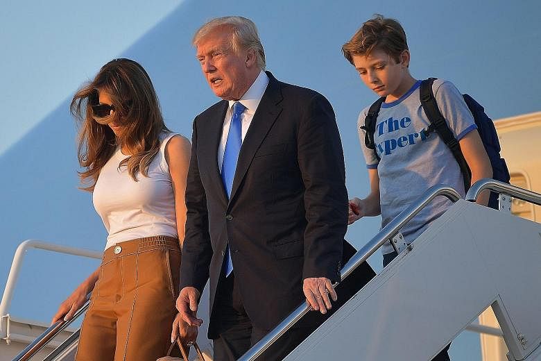Mr Donald Trump with his wife Melania and son Barron leaving Air Force One at Joint Base Andrews. Mrs Trump and Barron had stayed in New York so Barron could complete the school year.