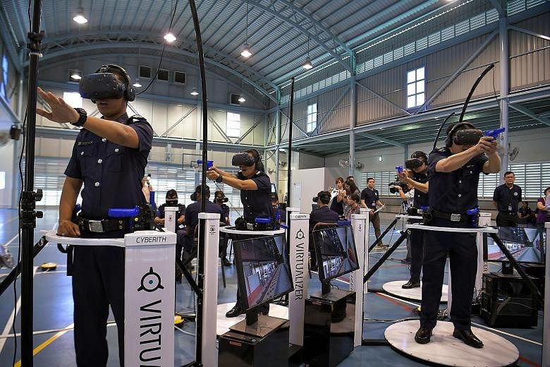 Police officers on omni-directional treadmills demonstrating simulation training with head-mounted displays at the Bedok Police Division on Monday. The set-up enables users to move around in a virtual world. Such training is increasingly becoming imp
