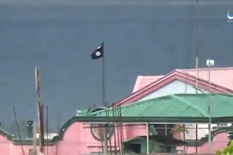 A screen grab of a video posted on ISIS-affiliated Amaq News Agency's social media site on Monday shows a black flag on a building in Marawi. Maute and Abu Sayyaf militants still control 20 per cent of Marawi, more than twice the area the military ci