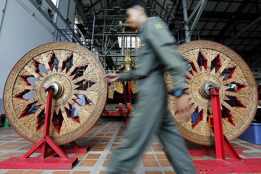 These wooden angels (above) and wheels (right), as seen yesterday at the National Museum in Bangkok, will be part of the Royal Chariot to be used for the late Thai King Bhumibol Adulyadej's funeral ceremony. 	The Royal Chariot (right, in background) 