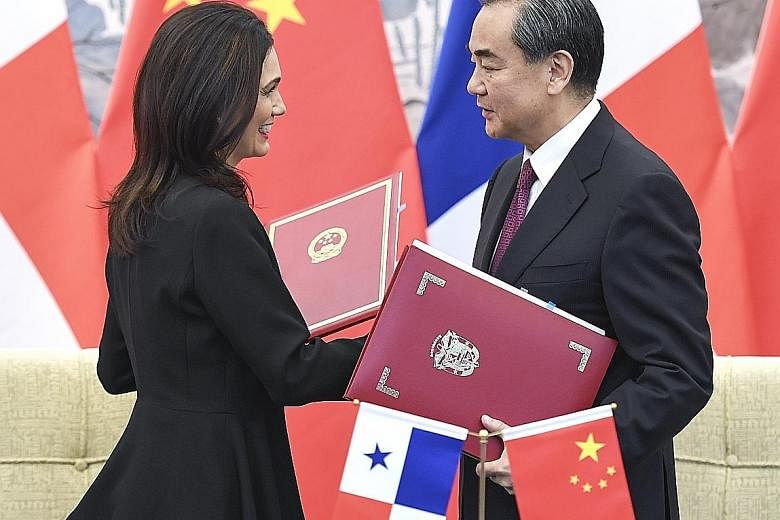 Panamanian Vice-President and Foreign Minister Isabel Saint Malo exchanging documents with Chinese Foreign Minister Wang Yi in Beijing yesterday after signing a joint communique on establishing diplomatic relations.