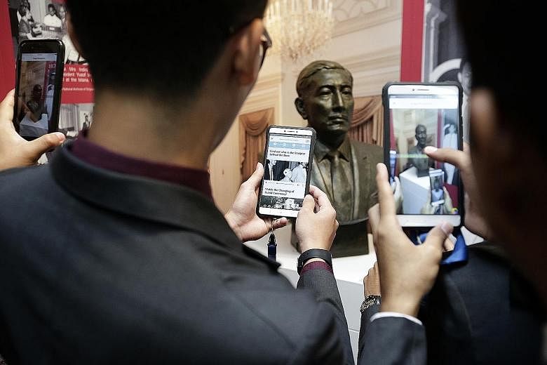 Temasek Polytechnic students using the LocoMole app to scan a bust of former president Yusof Ishak, which then enables them to play a video on its sculptor, at the Istana Heritage Gallery yesterday. They were on the Istana Heritage Gallery Trail, one