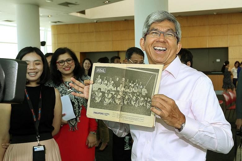 Dr Yaacob Ibrahim at the Contributing to Singapore's History event held by the National Library yesterday. The minister is holding a picture of the Singapore team which won the 1977 Malaysia Cup. Dollah Kassim, who was part of that team, was one of t