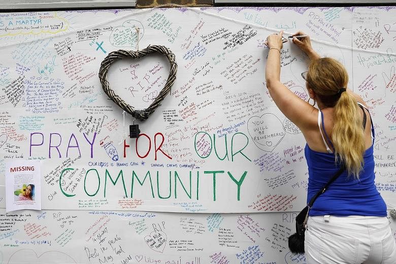 A well-wisher writing on a wall bearing condolence messages on Wednesday, after the blaze at Grenfell Tower in west London.