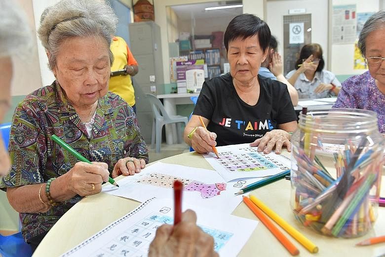 Ms Christel Goh with her grandmother, Madam Lily Teo, 80, who is showing signs of dementia. Ms Goh designed a card game for seniors to "fight" the disease. Madam Lucy Heng, 88, colouring a picture of a cheongsam alongside Madam Wong Lean Yew, 74, who