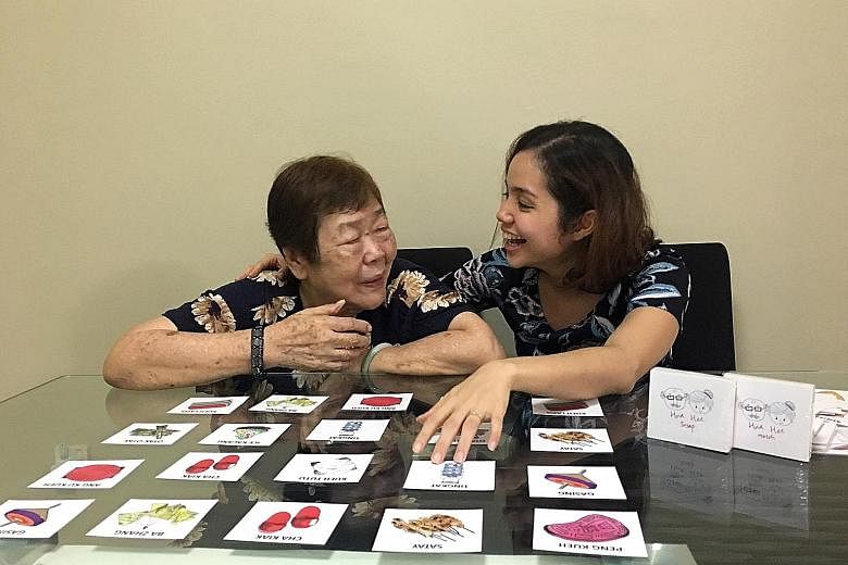 Ms Christel Goh with her grandmother, Madam Lily Teo, 80, who is showing signs of dementia. Ms Goh designed a card game for seniors to "fight" the disease. Madam Lucy Heng, 88, colouring a picture of a cheongsam alongside Madam Wong Lean Yew, 74, who