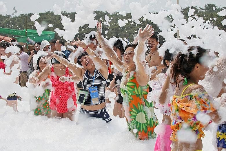 People playing with foam at a water park in Yantai, in China's Shandong province, yesterday. China's meteorological authority maintained its yellow alert - a heatwave is expected to sweep across many regions. Temperatures are expected to rise above 3