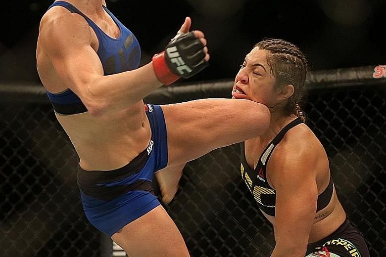 After a slow start that displeased the crowd, Holly Holm (left) catches Bethe Correia with a high kick that set the American on her way to victory in their bantamweight bout at the Singapore Indoor Stadium last night.
