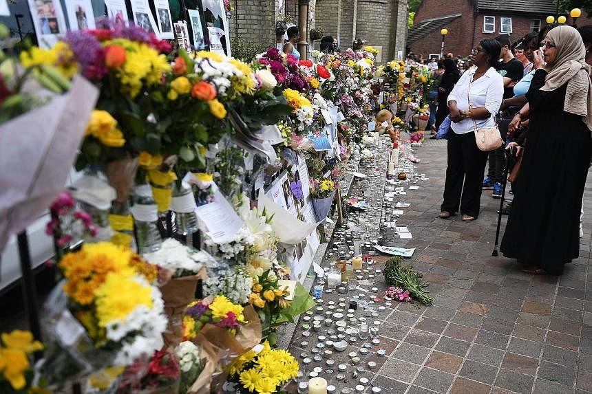 Passers-by reflecting silently at a makeshift shrine for the victims of the fire. Meanwhile, search and rescue workers continued to sift through the burnt-out remains of Grenfell Tower, a 24-storey apartment block in North Kensington, London, yesterd