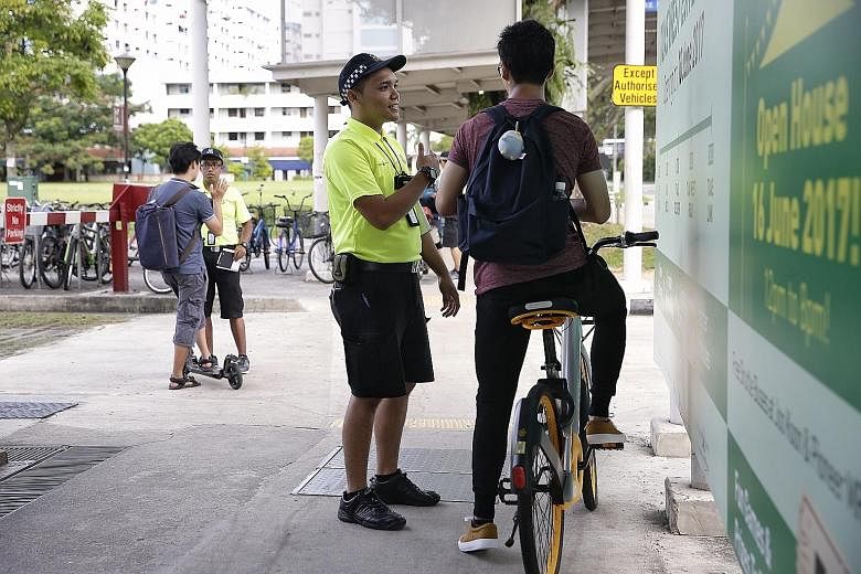 Active Mobility Enforcement Officer Asrul Fahmi Rashid advising a cyclist on safe riding habits while his colleague Shaik Shameer Ali speaks to an e-scooter user at Yishun MRT station.