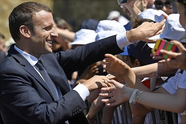 Mr Emmanuel Macron, whose party is projected to sweep into Parliament, shaking hands with people near Paris yesterday.