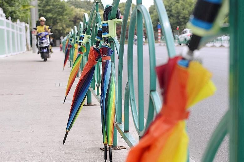 Rental umbrellas locked to a fence in Pudong district in Shanghai yesterday. A boom in bike-sharing and ride-hailing services has encouraged Chinese start-ups to share almost anything under the sun, from umbrellas and basketballs to concrete mixers, 