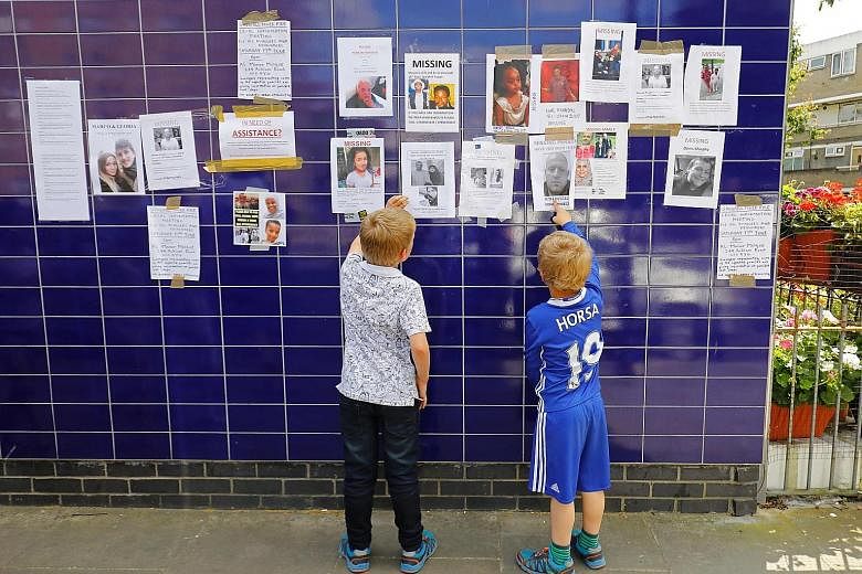 Posters of missing people after the Grenfell fire on display on a wall in Kensington on Saturday. Prime Minister Theresa May is facing pressure for keeping a distance from residents while visiting the site last week.
