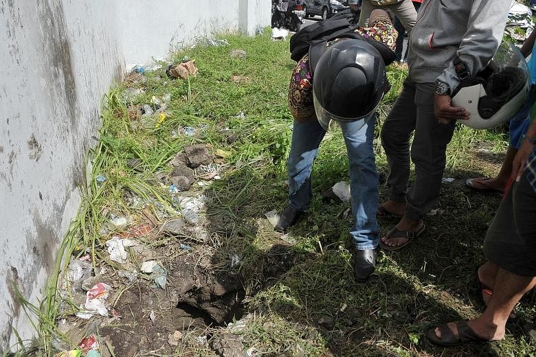 People looking into a hole outside Kerobokan Prison in Denpasar, Bali, yesterday. Four inmates made an audacious breakout via a 12m-long tunnel measuring 50cm by 75cm in cross section, Bali police said yesterday. The escape came just days after dozen