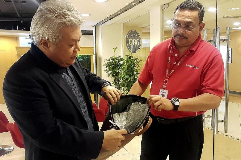 Sunway Malls' chief operating officer Kevin Tan (left) and security manager Adnan Adil Ariffin with one of the foil-lined bags used by a shoplifter.