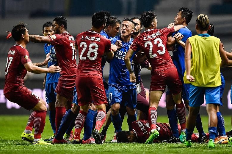 A brawl erupts between Shanghai SIPG players (in red) and Guangzhou R&F players (in blue) as Oscar lies prostrate on the pitch. The Brazilian international midfielder had instigated the incident after twice firing the ball at R&F players in a deliber