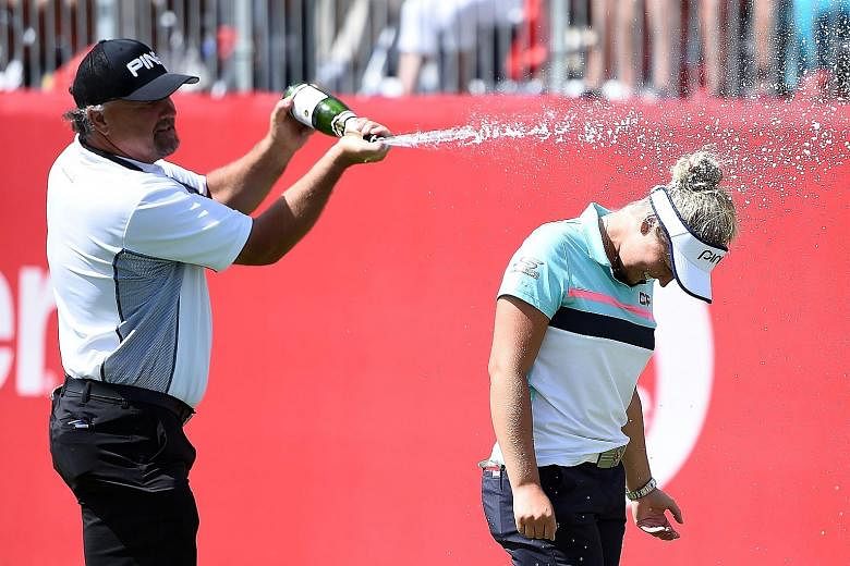 Canadian teen Brooke Henderson is sprayed with champagne by her father Dave, who is also her coach, after finishing with a 17-under 263 to win the Meijer LPGA Classic at Blythefield Country Club by two strokes from Lexi Thompson and Michelle Wie.