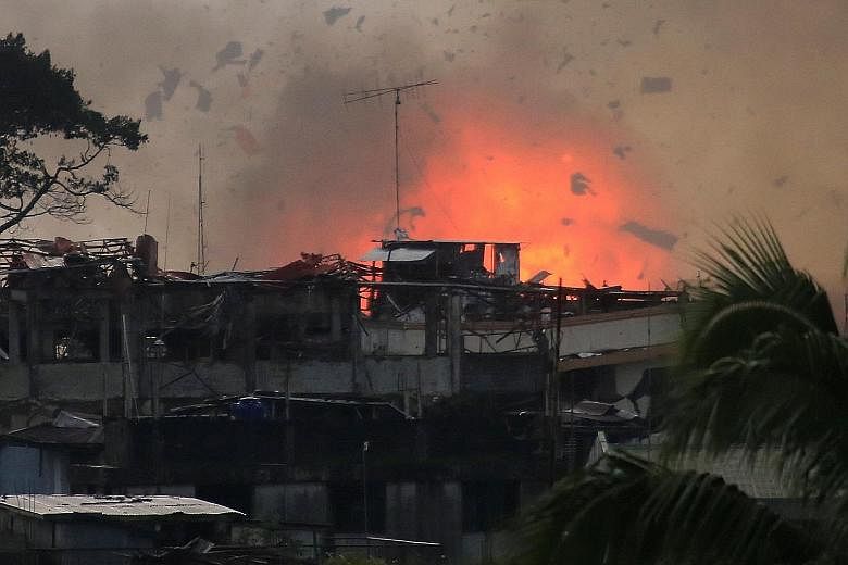 Above: Debris is sent flying into the air after a bomb explodes in Marawi City after an air strike by an OV-10 Bronco aircraft yesterday, as government forces continued their assault against Muslim militants. More than a hundred gunmen from militant 