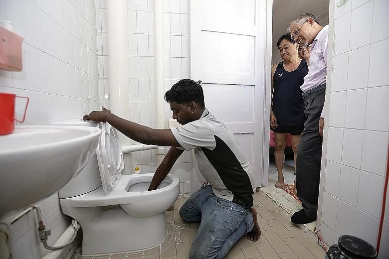 Minister for the Environment and Water Resources Masagos Zulkifli and home owner Teo Oon Peng watching as a worker installed a water-efficient dual-flush toilet in Mr Teo's Tampines flat yesterday.