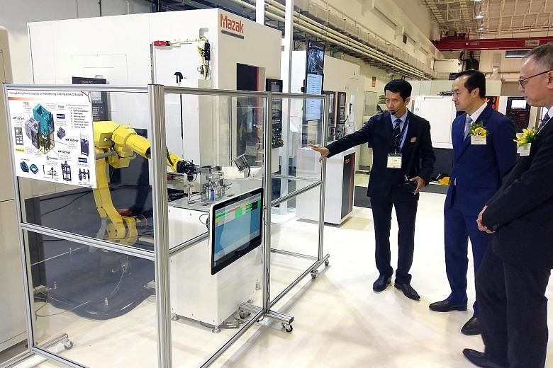 Senior Minister of State for Trade and Industry and National Development Koh Poh Koon (right) learning about the high-tech production equipment at Yamazaki Mazak's manufacturing plant in Singapore from Mr K. S. Chong, senior director, Yamazaki Mazak 