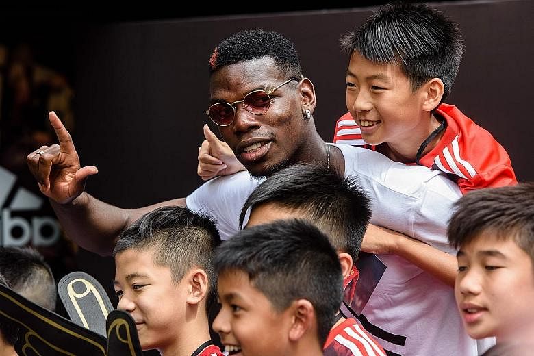 Manchester United midfielder Paul Pogba (left) posing with Hong Kong fans during a promotional event for adidas Tango League, a three-on-three football game, on Monday. Below: Pogba holding up a custom-made sign reading "Pogba and Hong Kong" in Chine