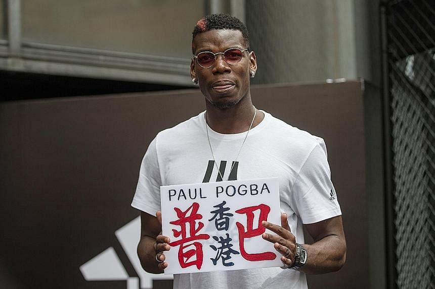 Manchester United midfielder Paul Pogba (left) posing with Hong Kong fans during a promotional event for adidas Tango League, a three-on-three football game, on Monday. Below: Pogba holding up a custom-made sign reading "Pogba and Hong Kong" in Chine
