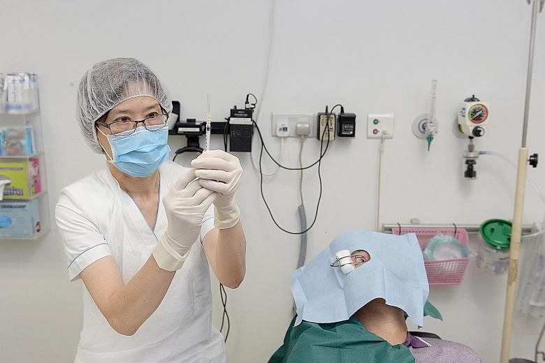 Senior staff nurse Chow Peck Foong preparing to administer an IVT injection on patient Han Boon Huat. Training nurses to do the procedure helps Tan Tock Seng Hospital meet the growing demand for such shots.