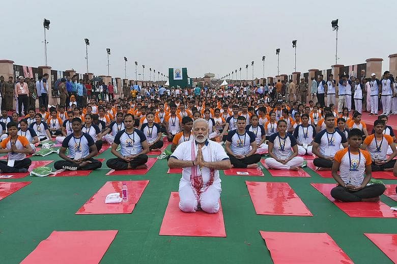 Above: Indian Prime Minister Narendra Modi leading a yoga session in Lucknow yesterday . Left: A yoga session on board India's aircraft carrier INS Vikramaditya.