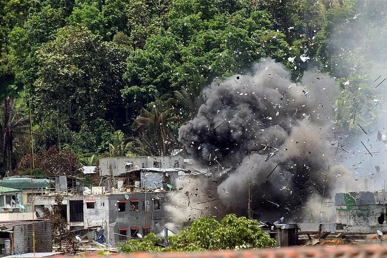 Debris and smoke shroud a building as government forces continue their assault against insurgents who have taken over large parts of Marawi City.