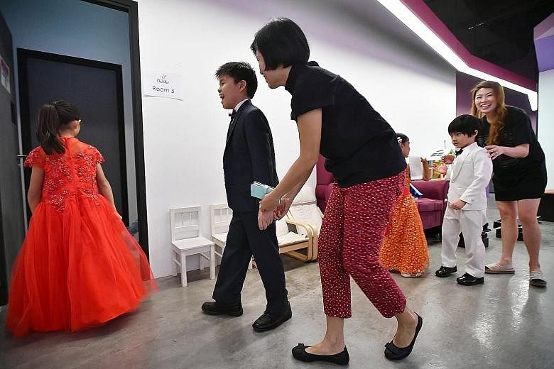Madam Jenny Chan (centre) giving her son, Ryan Phuan, and his friend, Kion Chew (left), both nine, moral support and encouragement before their piano duet audition yesterday.