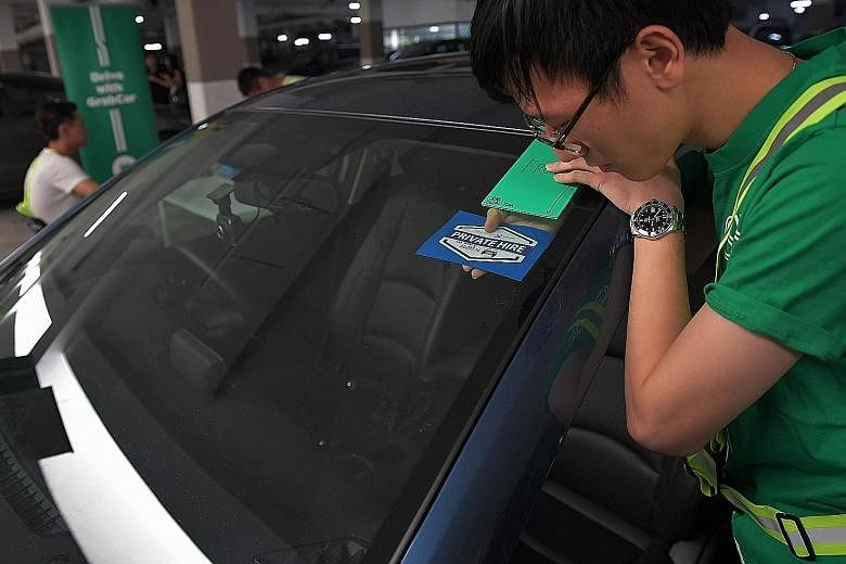 Above: A Grab employee applying the Private Hire Car Driver's Vocational Licence decal to a car yesterday. About 27,000 cars have had such decals affixed. Left: The word "void" appears on both sides of the tamper-evident decal once it is peeled off, 