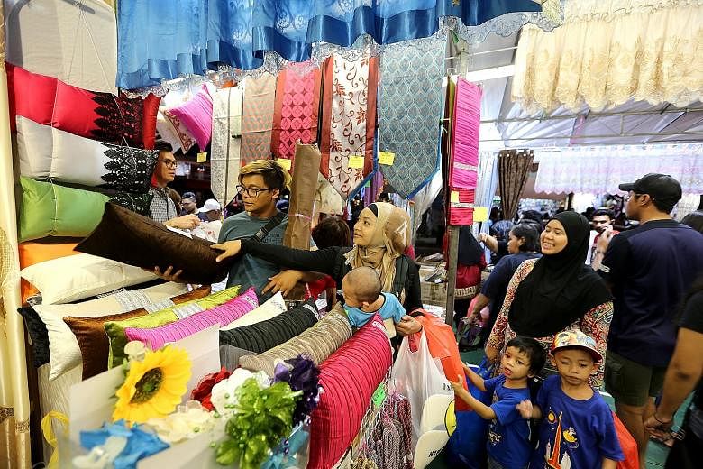 Madam Fatin Shazwani (centre) and her family getting some last-minute Hari Raya Aidilfitri shopping done at the Geylang Serai Bazaar last night. The month-long bazaar, which was into its final night, was jam-packed with people hoping to pick up barga