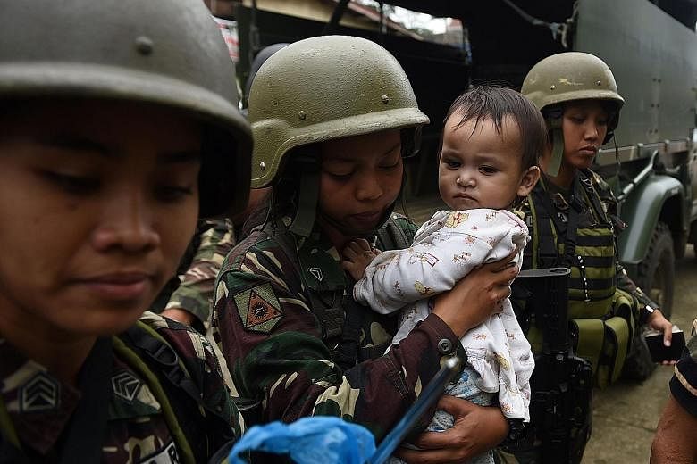 Philippine army troops with a rescued child in war-torn Marawi yesterday. Muslim religious leaders entered the conflict zone yesterday and negotiated with militants to release some civilian hostages.