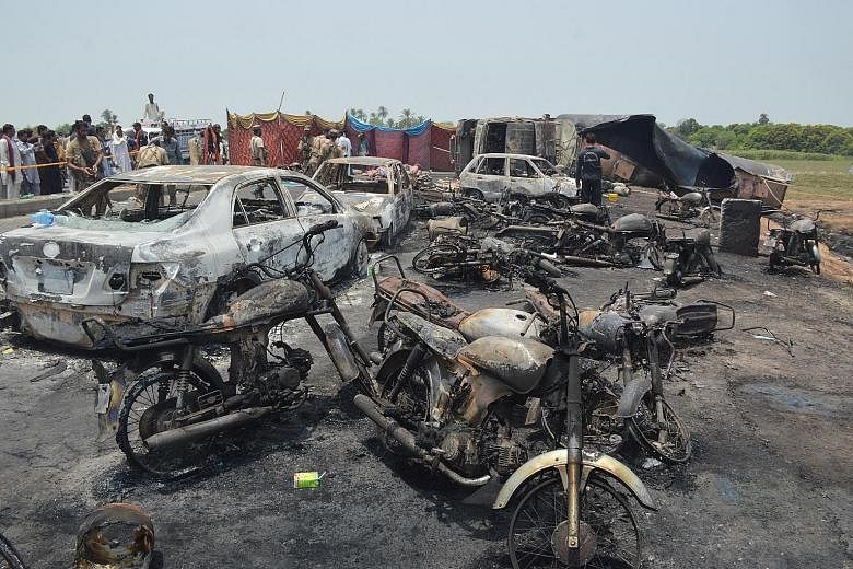 The aftermath of a huge explosion caused when leaking fuel from a tanker, which had crashed on the outskirts of Bahawalpur in Pakistan yesterday, ignited in a huge fireball. Many of the victims of the blast were people who had gathered with container
