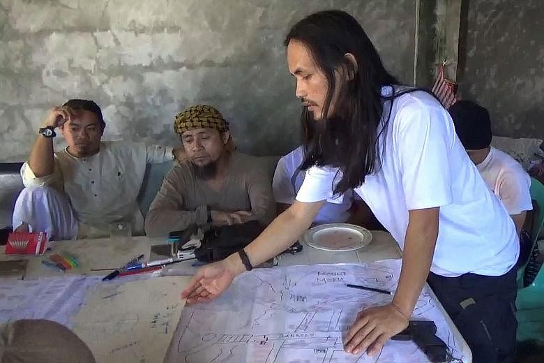 A screengrab from a handout video released by the Philippine Army earlier this month showing Abdullah Maute (right) and Isnilon Hapilon (centre) as they plan an attack on Marawi.