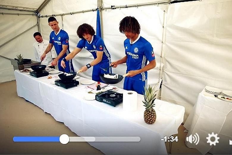 Chelsea defenders Gary Cahill, David Luiz and Nathan Ake (L to R) frying up char kway teow, under the guidance of north London restaurant Singapore Garden's head chef, Toh Kok Sum.