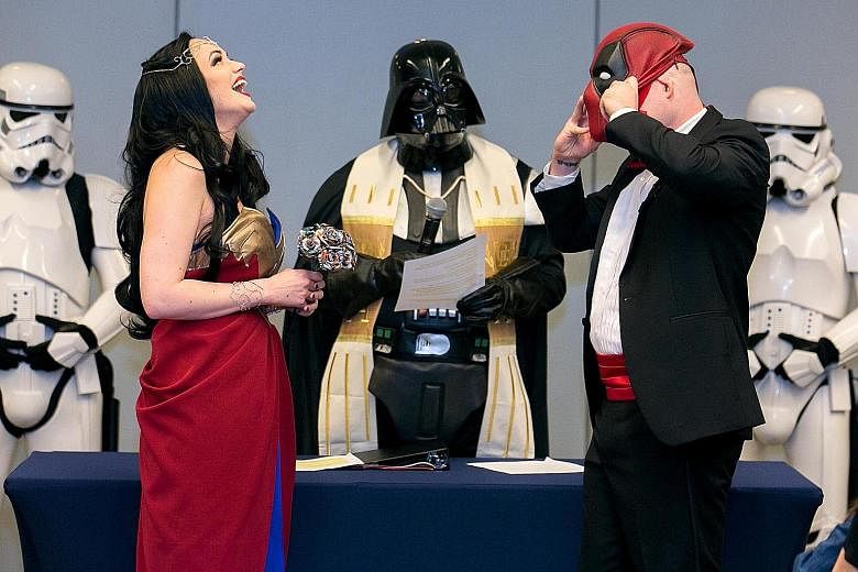 Mr Adam Merica removing his Deadpool mask to address his bride, Ms Megan Mattingly, who was dressed as Wonder Woman at their wedding at Awesome Con in Washington, DC on June 17. Their officiant was dressed as Darth Vader, while the wedding party were