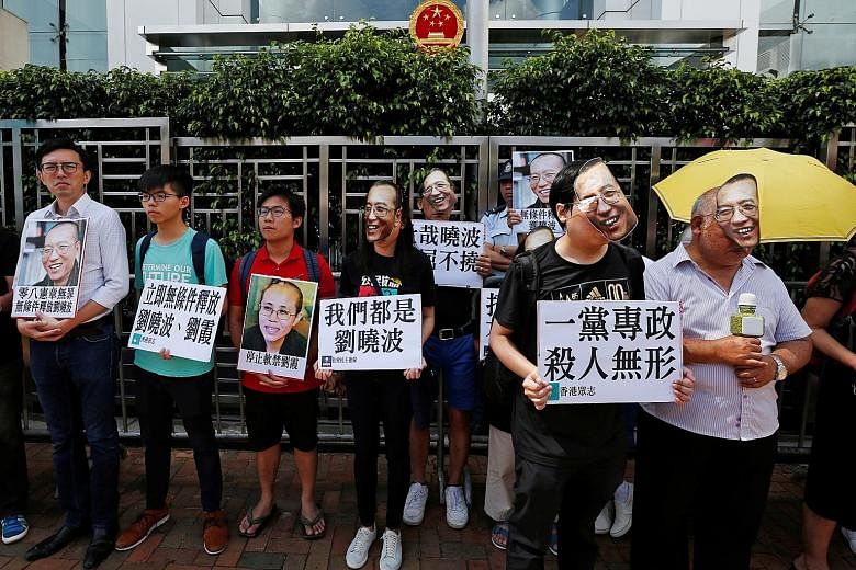 Supporters of Mr Liu Xiaobo, some wearing masks bearing his face, protesting outside China's Liaison Office in Hong Kong yesterday.