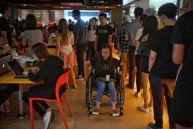 Business student Celine Lee, 18, who is able-bodied, balancing a tray with a cup of water yesterday while using a wheelchair in the Ngee Ann Polytechnic canteen. The poly yesterday launched a month-long campaign to foster a more inclusive and respect
