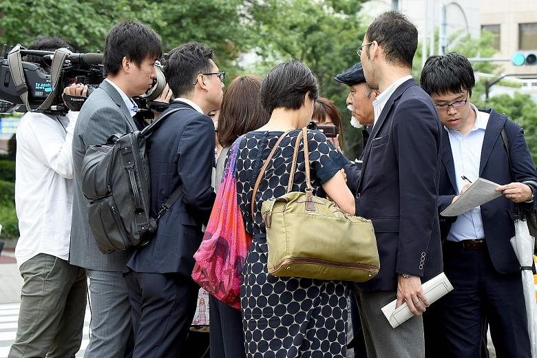 A shareholder (third from right) being interviewed outside the venue of Takata's shareholders' meeting in Tokyo yesterday, a day after the firm filed for bankruptcy protection.