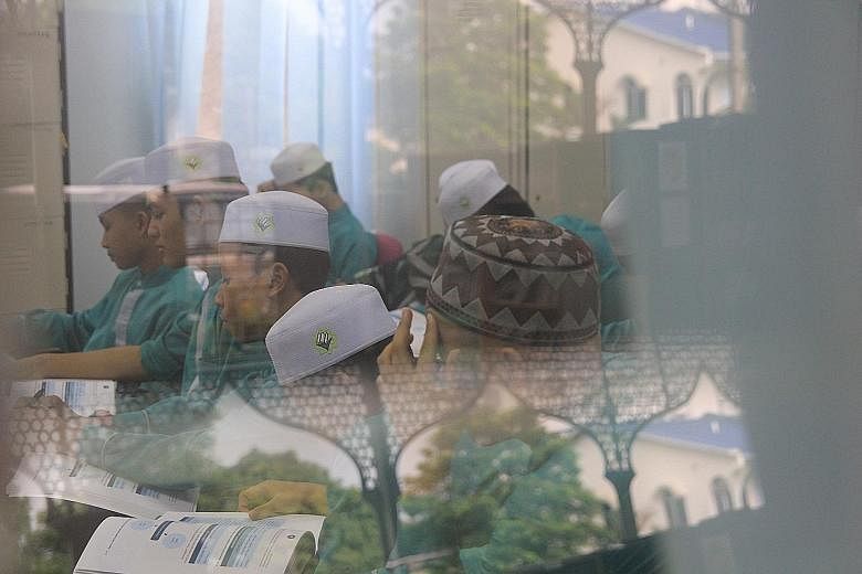 Muslim girls at a tahfiz - which means "memorising" (the Quran), where classes go on into the night. Below: Muslim boys at a religious school, many of which are in residential neighbourhoods. Many tahfiz schools do not provide a parallel system for s