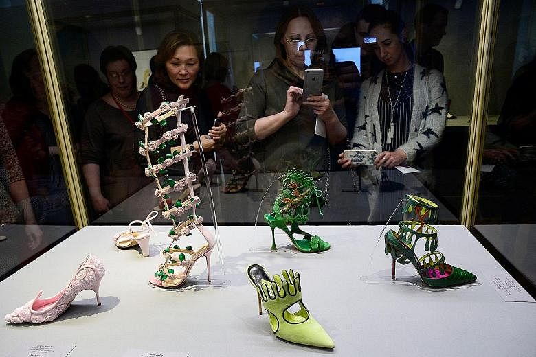 Visitors looking at creations by Spanish fashion designer Manolo Blahnik at an exhibition in Russia last month. Instead of heels, women are now buying shoes they can wear year-round.