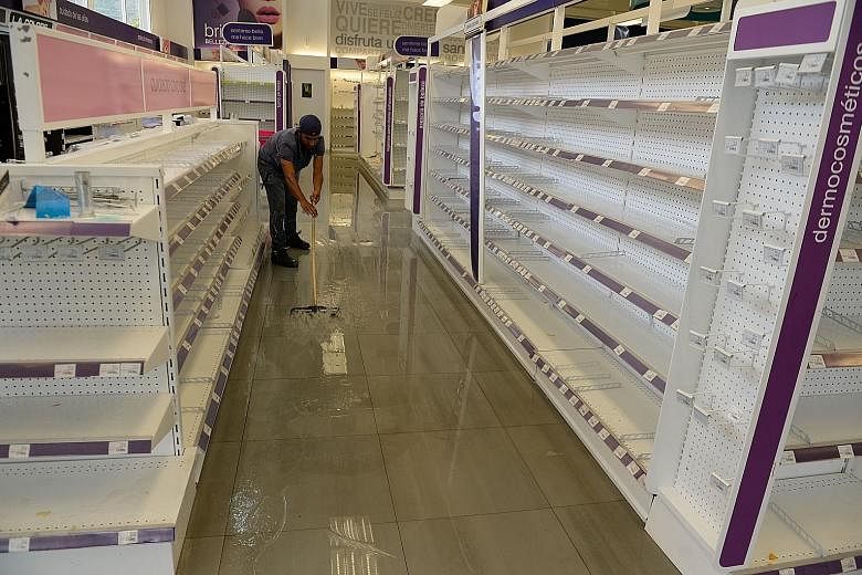 An employee cleaning the aisles of a looted pharmacy in Maracay, Venezuela on Tuesday. The country has been gripped by months of protests against President Nicolas Maduro.